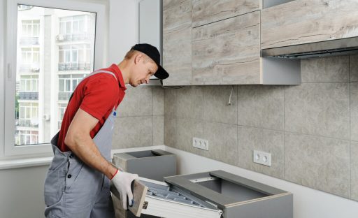 Installation of kitchen. Workman sets the drawer in cabinet.